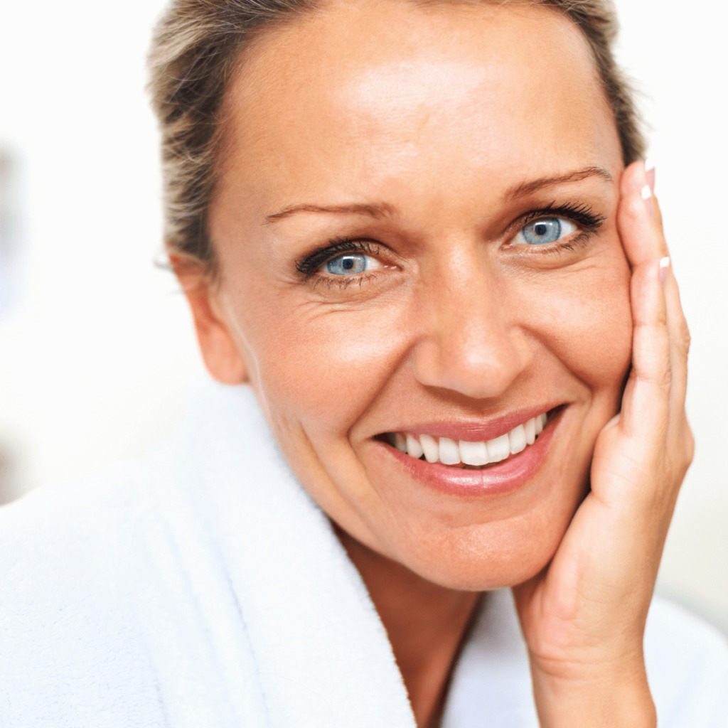 Middle aged woman smiling and touching face