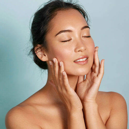 Asian woman touching face after face resurfacing treatment