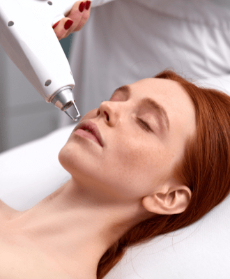 Young beautiful woman lying with her eyes closed while having face laser treatment