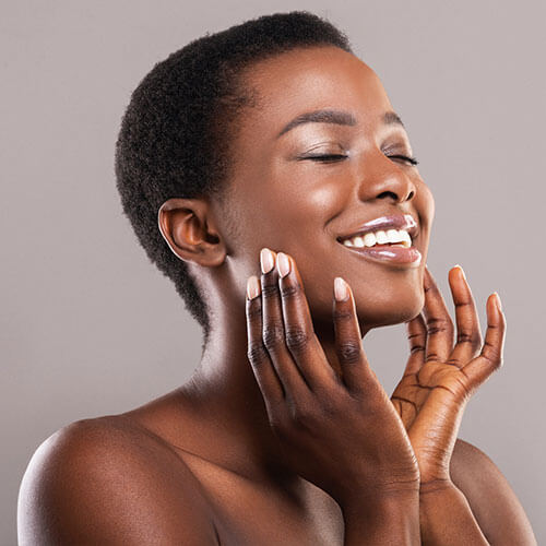 Young black woman feeling her skin after rejuvenation treatment