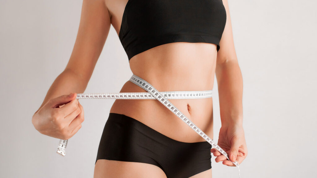 Woman in black bikini with tape measure around waist