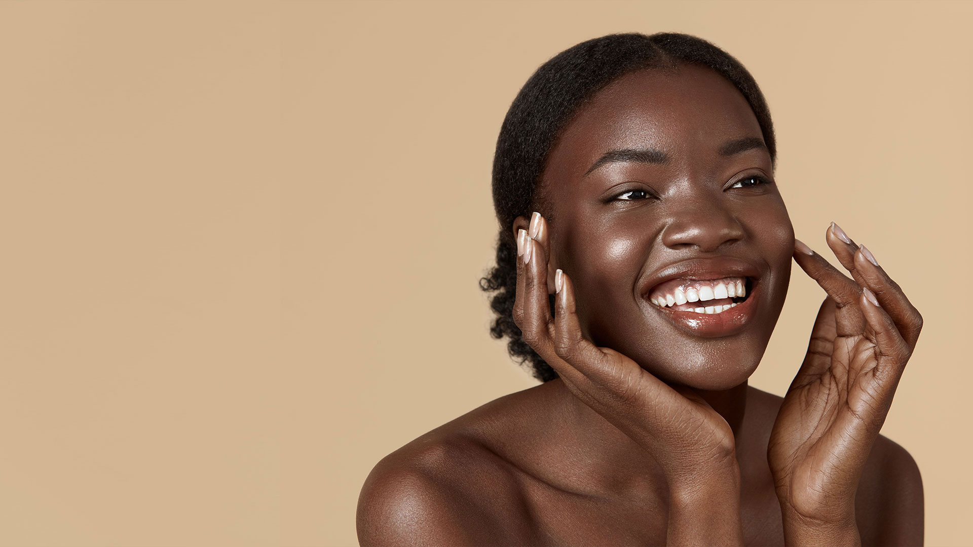 Beautiful black woman touching cheek and smiling due to microdermabrasion treatment